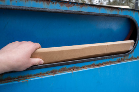 Hand throw a cardboard box at blue paper container