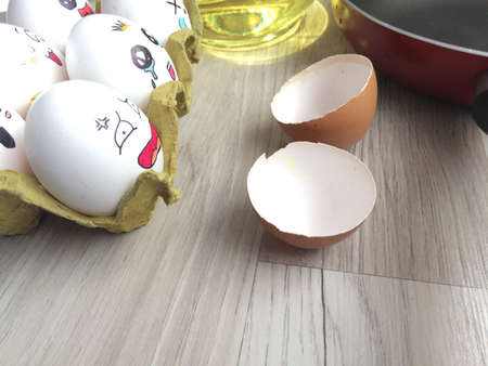 Scared egg, cracked egg, pan and oil on a wooden floor