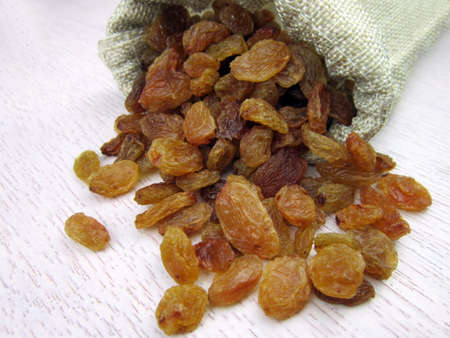 Raisins in burlap bag on wooden tableの写真素材