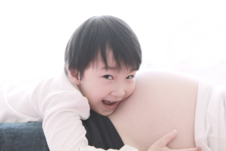 a photo of asian boy listening belly pregnant on white backgroundの写真素材