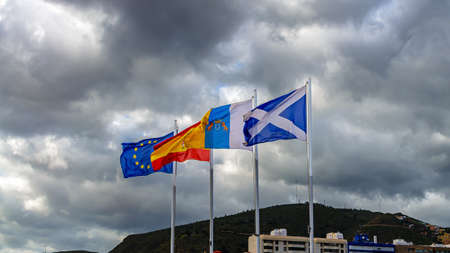 Against a dramatic sky with rain clouds the flags are waving in the wind.の写真素材