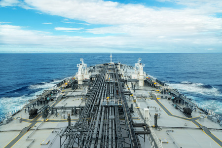 Grey and white tanker proceeding through blue sea under skyの写真素材