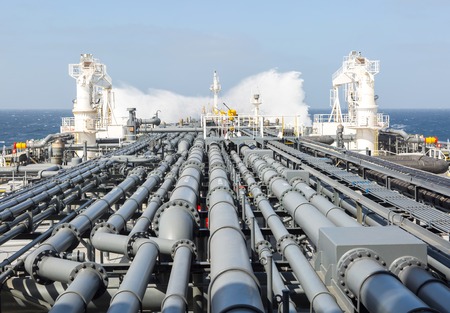 Crude oil tanker pipeline and breaking wave during stormy weather.