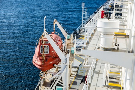 Orange lifeboat of cargo ship underway in the ocean.の写真素材