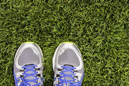 Silver running shoes on green grass of stadium.の写真素材