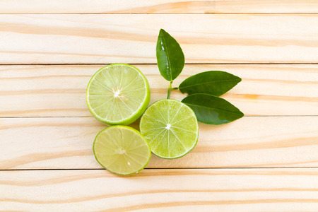 Limes slices and green leaves on wooden backgroundの写真素材