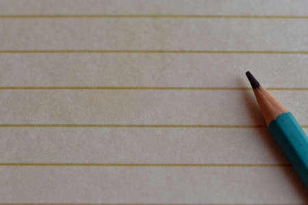 a sharply sharpened pencil lies on lined paper. copy spaceの写真素材