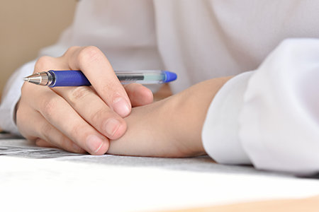 the school girls hand is holding a pen. crossword puzzleの写真素材