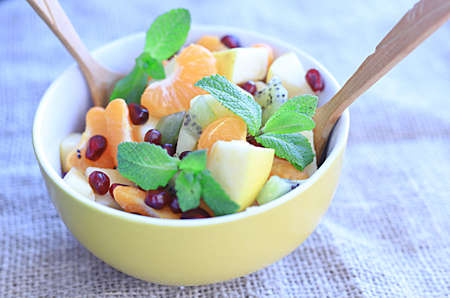 fruit salad of tangerines kiwi apples pomegranate seeds. healthy eatingの写真素材