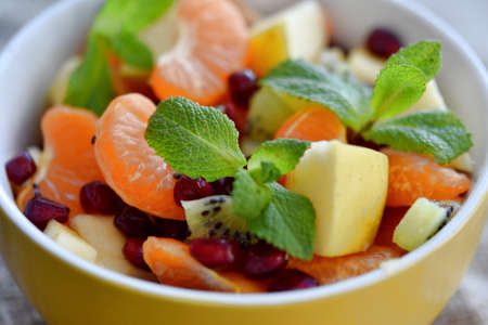 fruit salad of tangerines kiwi apples pomegranate seeds. healthy eatingの写真素材