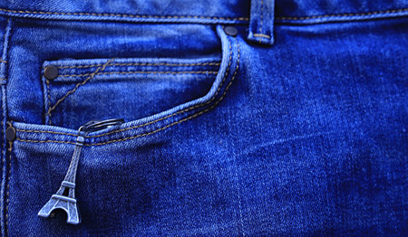 keychain in the shape of an eiffel tower hanging from the pocket of blue jeans. carelessness conceptの写真素材