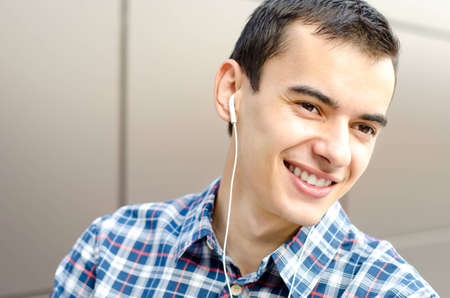 Portrait of handsome young man listening to music, smiling and looking away