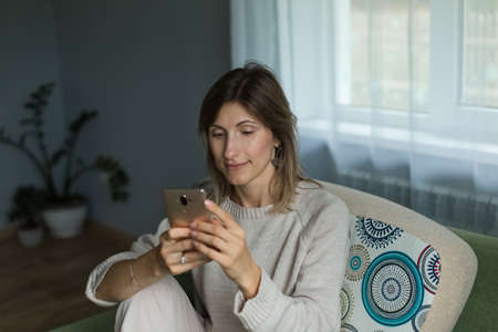 A beautiful girl sits and looks thoughtfully into the phone into the phone.