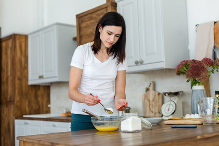 Girl prepares a meal, whisking the mixture with flour with a whisk.