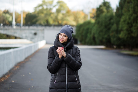A girl stands on the embankment near the water, in warm clothes.の写真素材