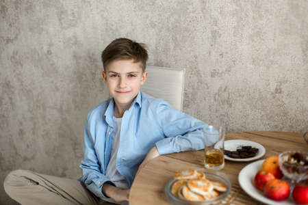 Child sits at the table in the kitchen and looks at the camera.の写真素材