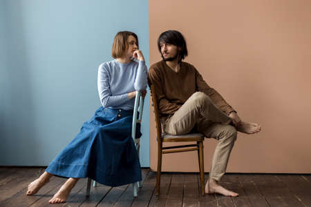 Guy and girl are sitting on chairs close to each other.の写真素材