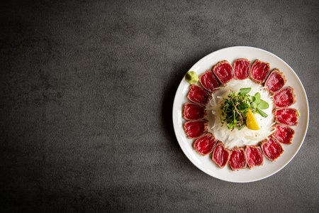 Beef carpaccio on a white plate on a dark backgroundの写真素材