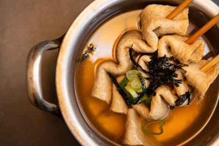 Dumpling soup in a pot with chopsticks on the tableの写真素材