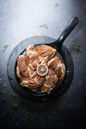 Raw pork meat in a frying pan on a black background, top viewの写真素材