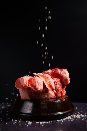 Raw pork meat with salt on black background. Selective focus.の写真素材