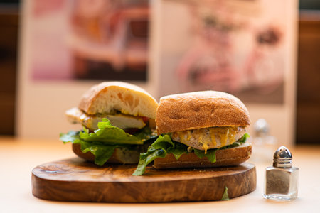 Sandwich with chicken and cheese on wooden board, selective focus.