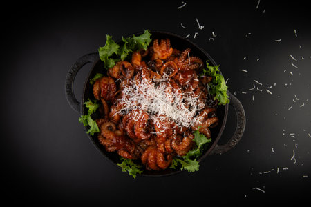 Fried squid with cheese in a black bowl on a black background