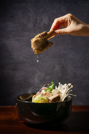 Beef noodle soup in bowl on wooden table over dark background