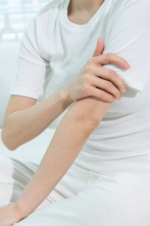 Closeup of woman applying cream on her arm in the living room