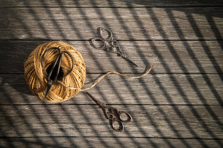 Old scissors and thread on a wooden background. View from above.