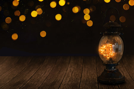 Lantern on wooden table with bokeh lights background.