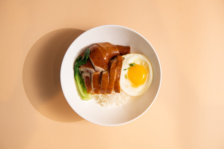Rice with pork and egg in white bowl on brown background.