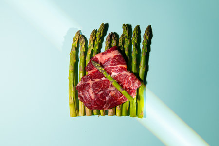 Asparagus with raw beef steak on a blue background with sunlightの写真素材