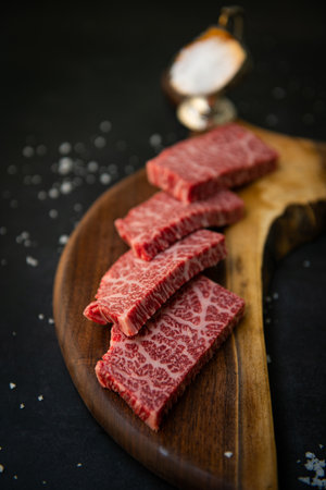 Raw wagyu sirloin beef steak on wooden cutting board on black backgroundの写真素材