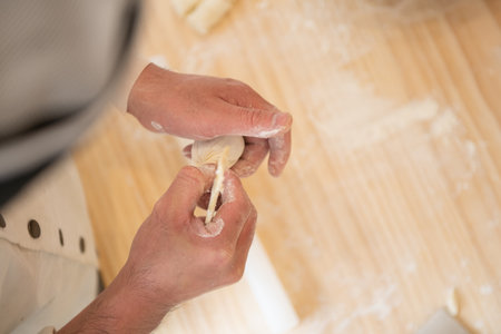Closeup of chef hands kneading dough on wooden cutting board