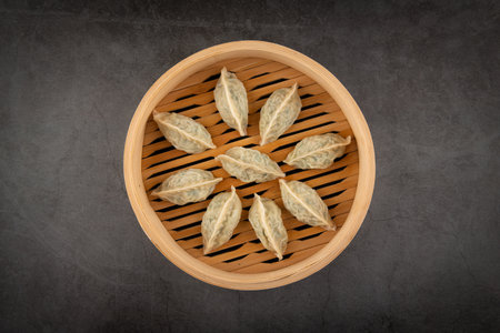 Chinese dumplings in bamboo steamer on blackboard background.の写真素材