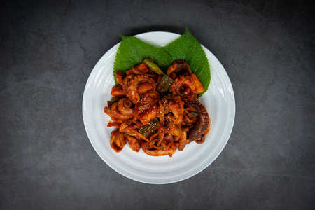 Korean food, stir-fried squid with spicy sauce on black background
