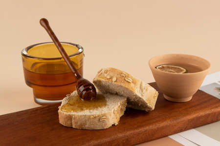 Honey and bread on a wooden board on a beige background