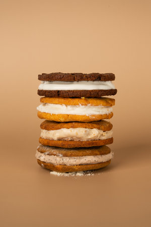 Stack of chocolate cookies with whipped cream on a beige background.の写真素材