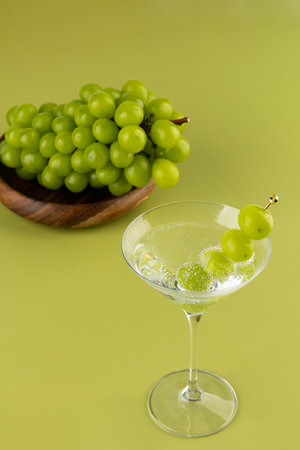 Green grapes in a martini glass on a green background with copy spaceの写真素材