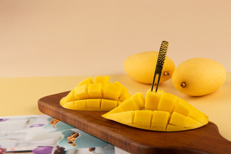 chopped ripe mango on a wooden cutting board on a yellow backgroundの写真素材