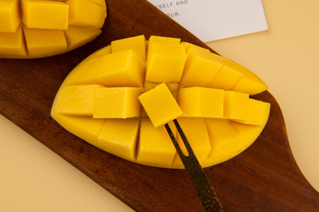 chopped mango on a wooden board with a knife, closeup