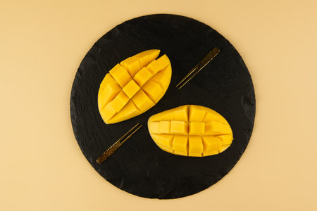 Mango fruit on a black slate plate on a yellow background.の写真素材