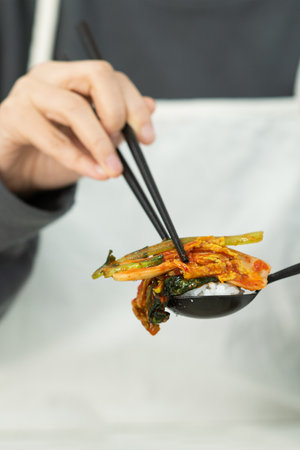 Chef holding chopsticks with kimchi and rice on white backgroundの写真素材
