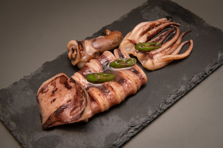 Grilled squid on black slate plate. Seafood restaurant menu.