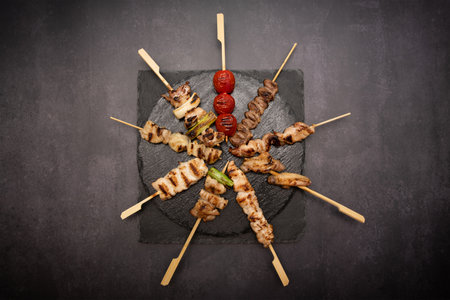 Grilled meat on skewers with vegetables on black background. Top viewの写真素材