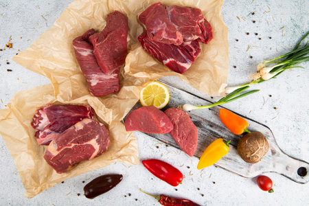 Raw beef meat with spices, herbs and vegetables on a white backgroundの写真素材
