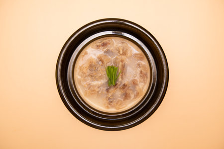 Chinese steamed dumpling soup in black bowl on yellow background