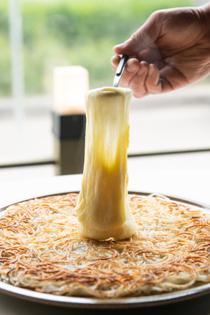 Chef decorating noodles in white dish on the table.