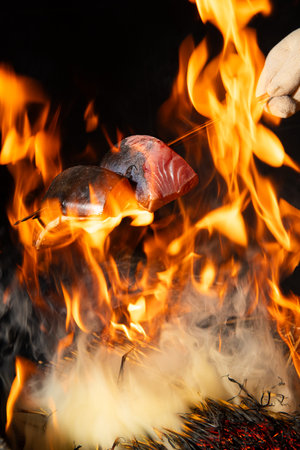 Close-up of a man's hand in a white glove holding a piece of salmon on a fire.の写真素材